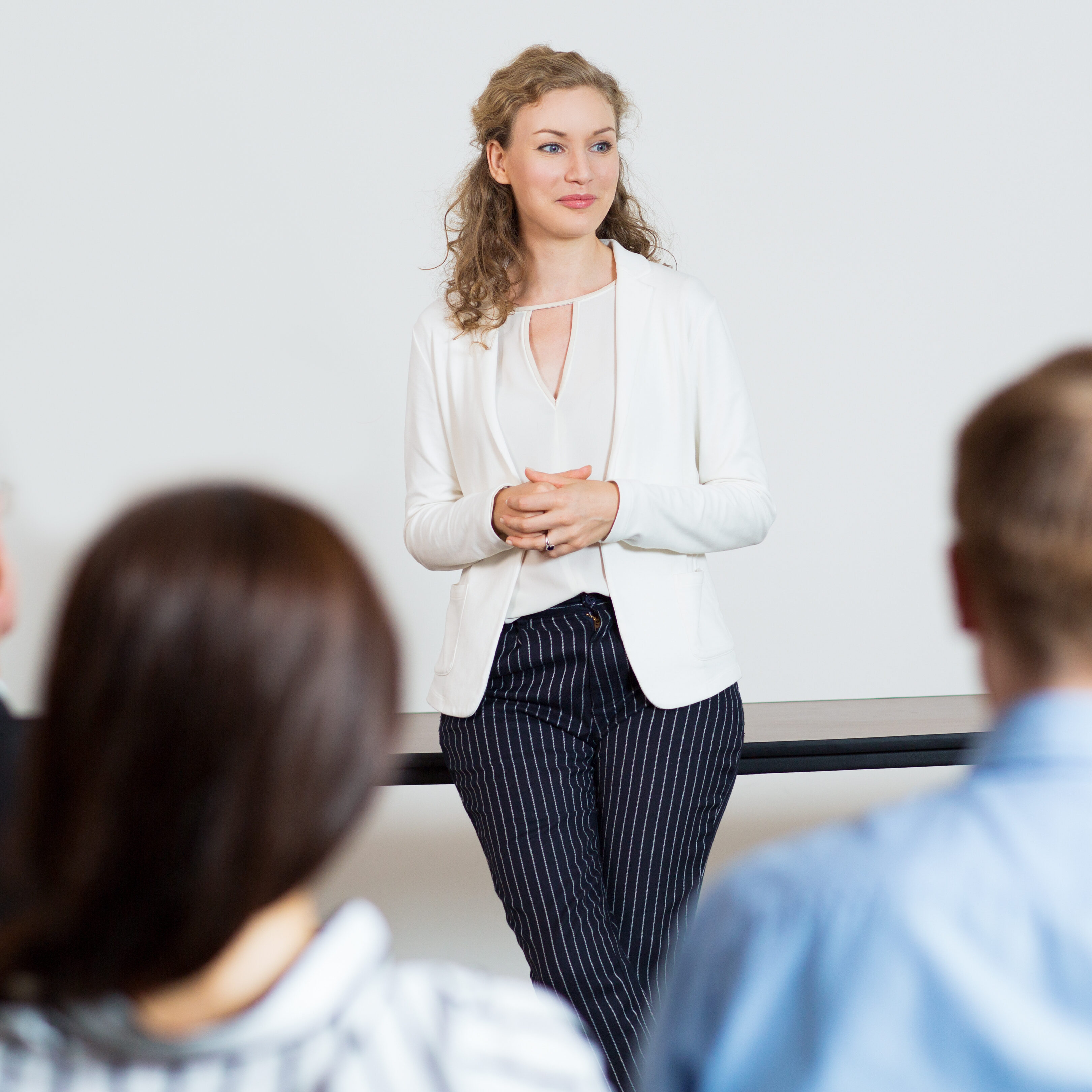 Portrait of young female businesswoman standing in conference room and listening to question. Business presentation concept